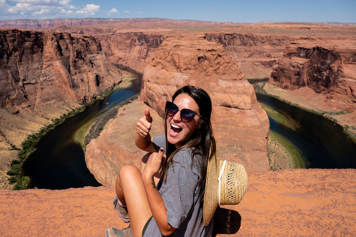A woman sitting on a ledge near Horseshoe, Bend in Arizona in the United States