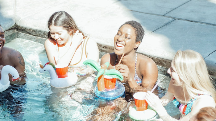 Three women laughing and having drinks in a pool