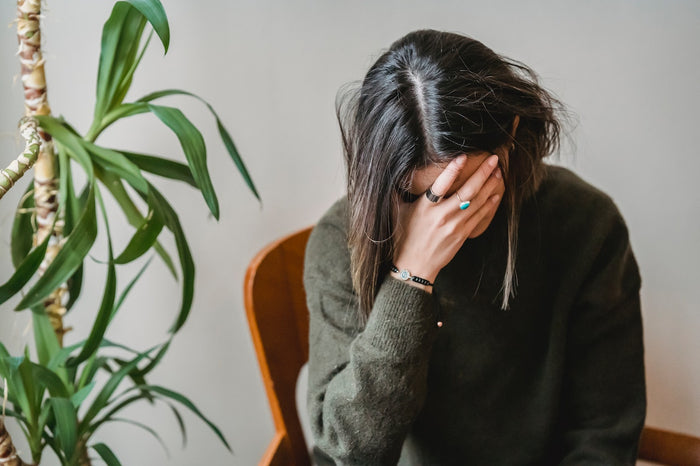 A woman experiencing menstrual problems and asking herself, “Can stress cause heavy periods?”