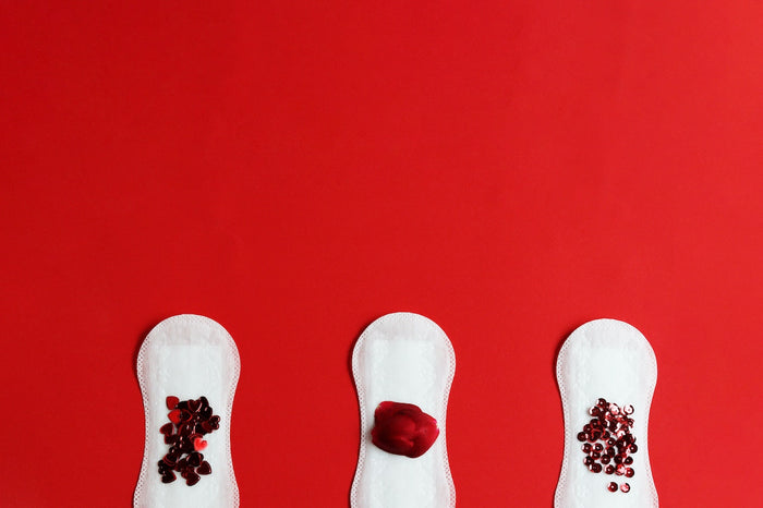 Red seeds and clots on three white sanitary pads to represent the best pads for heavy periods
