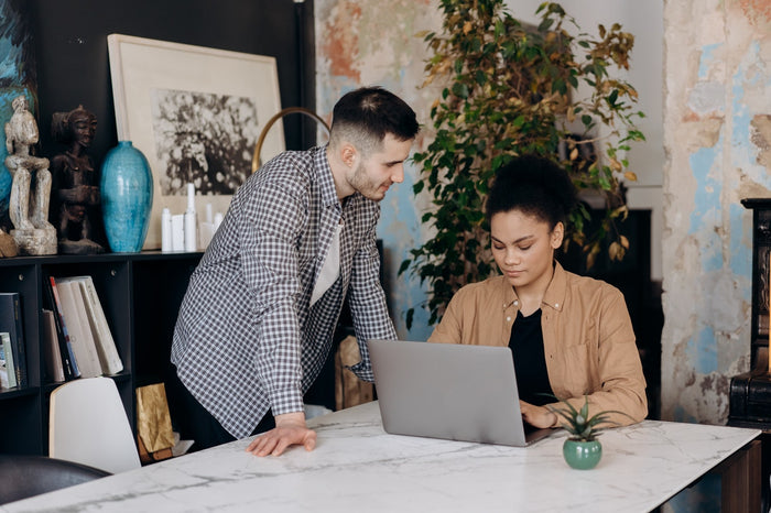 A man making jokes while a woman is using her laptop