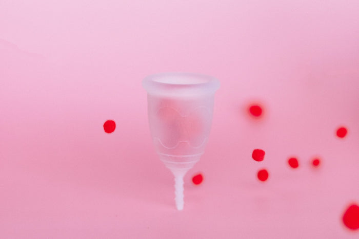 A photo of an upright menstrual cup with red dots around it